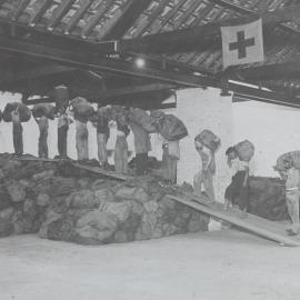 Men carrying Red Cross parcels in single file