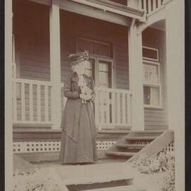 [Woman standing outside house]