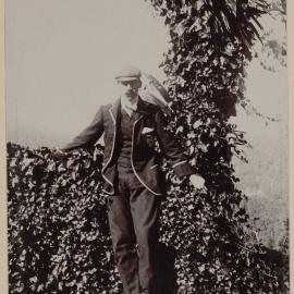 [Man posing in front of hedge]