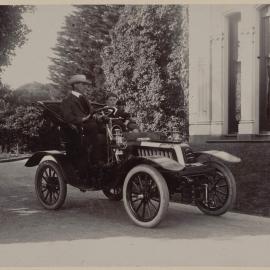 [Man and boy seated in motor car]