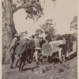 [Group of men standing around motor vehicle]