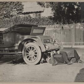 [Man laying under motor vehicle]