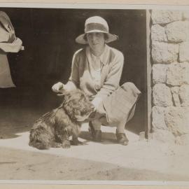 [Woman in crouched posed next to terrier dog]