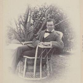 [Man seated on cane chair in garden,] Harleston